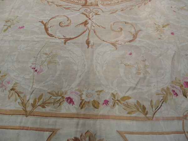 Low-pile rug detail showing large scrolling foliage, tan vines, and magenta roses on an ivory background.