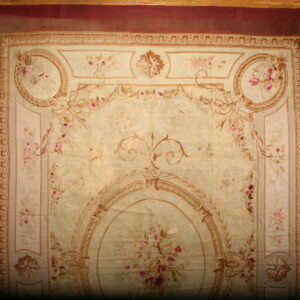 Large formal rug featuring a beige field, pink florals, tan scrolls, and a wide maroon border on a wood floor.