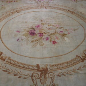 Ornate area rug featuring a pale background, pink floral bouquet, and a thick brown decorative oval border.