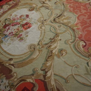 Low-pile rug detail showing floral bouquets and ornate scrolling patterns in red, sage, and cream.