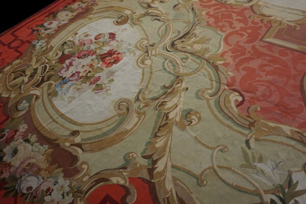 Low-pile rug detail showing floral bouquets and ornate scrolling patterns in red, sage, and cream.