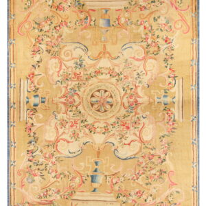 Tan low-pile rug featuring a dense neoclassical design of pink roses, blue urns, and scrolling cream foliage.