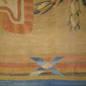 Muted tan textile with terracotta, olive green, and blue geometric patterns over horizontal colored stripes.