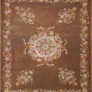 Brown rug featuring a detailed medallion surrounded by four floral bouquets and a border of pink roses.