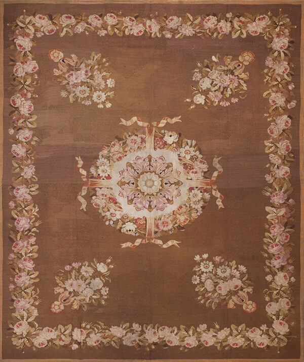Brown rug featuring a detailed medallion surrounded by four floral bouquets and a border of pink roses.