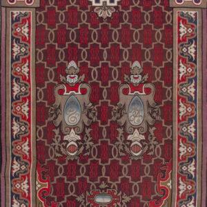 An ornate red and gray rug with a geometric lattice center and colorful symmetrical shield motifs.