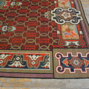 Colorful rug displaying complex floral borders and a maroon geometric field over distressed gray plank flooring.
