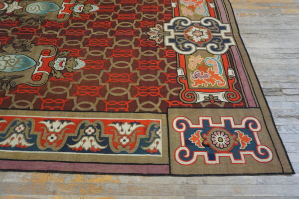 Colorful rug displaying complex floral borders and a maroon geometric field over distressed gray plank flooring.