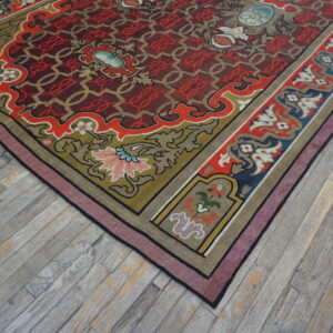 Ornate flatweave rug featuring a maroon geometric field and borders of olive green and navy blue on distressed gray wood.