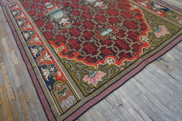 Low-pile rug with a complex red and maroon lattice field and highly detailed floral borders on gray wood floors.