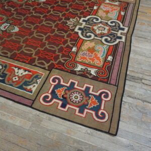 Highly detailed rug corner showing red geometric field, colorful borders, and distressed gray hardwood floor.