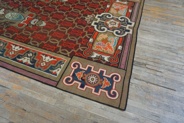 Highly detailed rug corner showing red geometric field, colorful borders, and distressed gray hardwood floor.