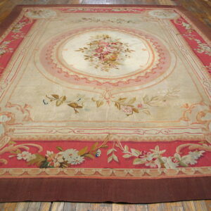 Large, low-pile rug featuring an ivory field, central floral medallion, and ornate pink and coral borders on a wood floor.