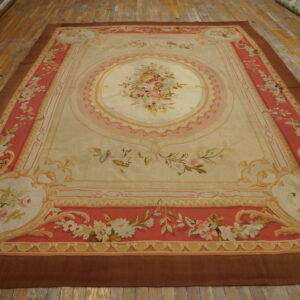 Ornate cream and coral flatweave rug featuring a central floral bouquet on worn wood planks.