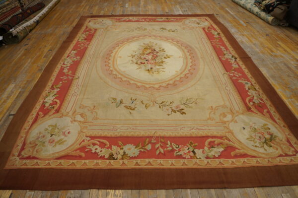 Ornate cream and coral flatweave rug featuring a central floral bouquet on worn wood planks.
