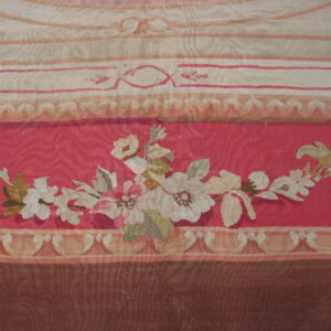 A tapestry-style rug detail features floral sprays on a salmon-pink ground bordered by pale stripes and brown trim.