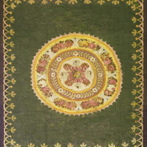 Green rug with a large circular pink and yellow floral medallion and repeating scalloped outer border.