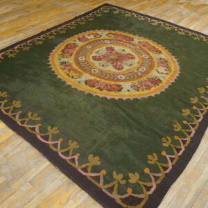 Dark green rug featuring a central multicolored floral medallion and patterned border on wood flooring.
