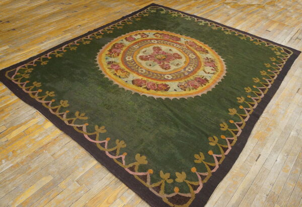Dark green rug featuring a central multicolored floral medallion and patterned border on wood flooring.