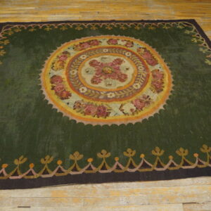 Dark green rug with a central floral medallion pattern on distressed yellow wood flooring.