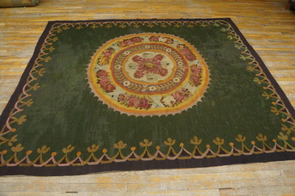 Dark green rug with a central floral medallion pattern on distressed yellow wood flooring.