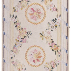 Flatwoven rug with a cream ground and pastel floral garlands, medallions, and striped decorative borders.