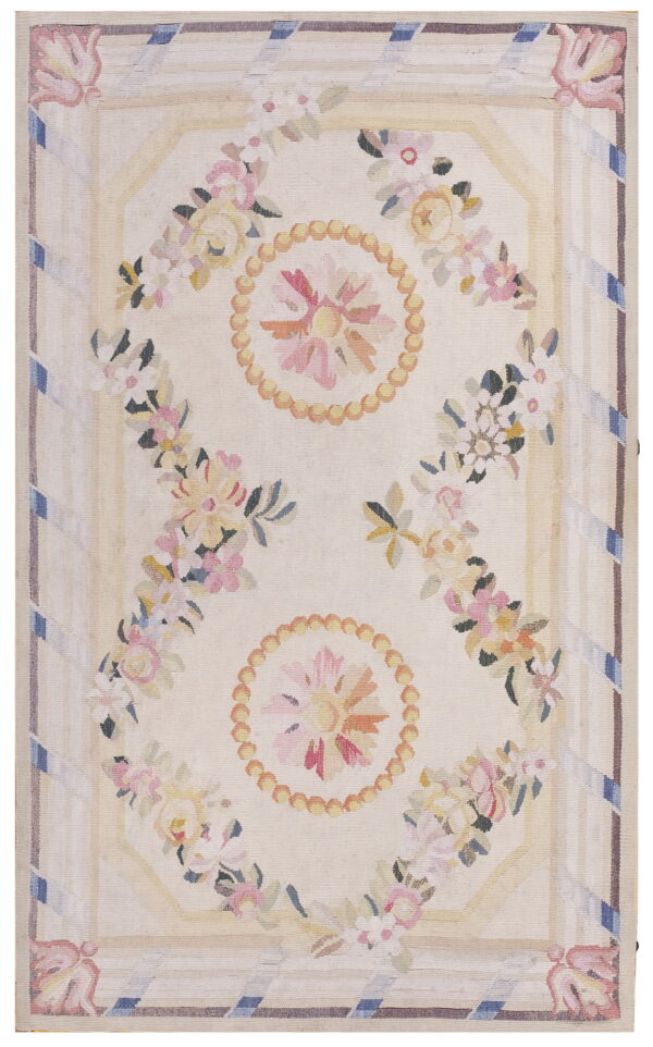 Flatwoven rug with a cream ground and pastel floral garlands, medallions, and striped decorative borders.