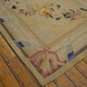 Flatwoven beige rug with soft floral and geometric motifs rests on distressed honey-toned wood floors.