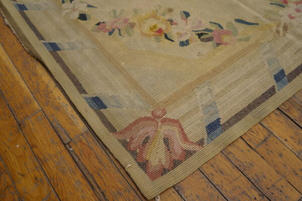 Flatwoven beige rug with soft floral and geometric motifs rests on distressed honey-toned wood floors.