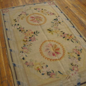 Floral flatweave rug featuring colorful pink and yellow designs on a pale field over wood floors.
