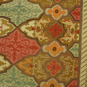 Flatweave rug detail with interlocking geometric medallions in green, gold, orange, and coral red tones.