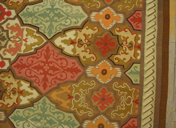 Flatweave rug detail with interlocking geometric medallions in green, gold, orange, and coral red tones.