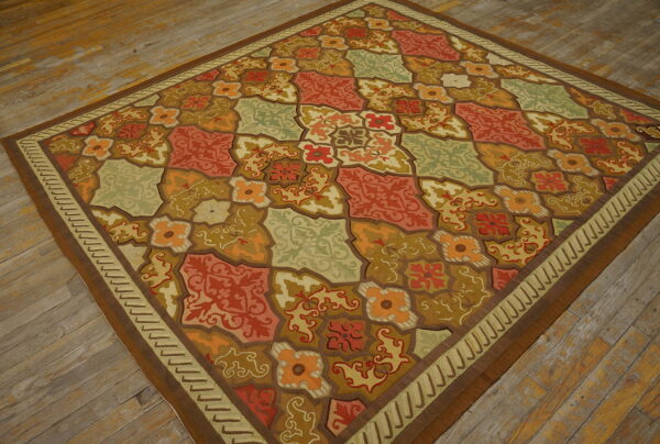 Multicolored rug featuring orange, red, and sage green tile-like floral patterns on distressed hardwood planks.