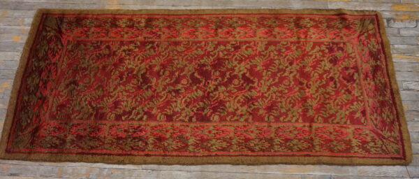 Red runner rug with a scrolling gold botanical pattern lies on weathered grey wood planks.
