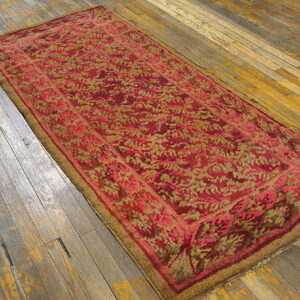 Red and gold floral patterned runner rug displayed on distressed, wide-plank wood flooring.
