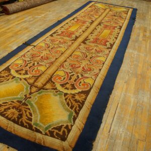 Ornate gold, orange, and brown runner rug with a navy border lies on distressed wooden flooring.