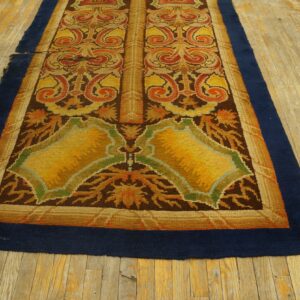 Ornate runner rug in gold, brown, and rust with a navy border lying on distressed light wood floors.