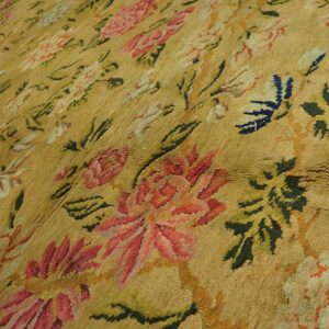 Mustard yellow rug with textured pile, patterned with large floral motifs in rose, olive green, and dark blue.