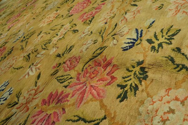 Mustard yellow rug with textured pile, patterned with large floral motifs in rose, olive green, and dark blue.