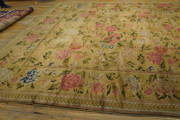 Distressed golden rug featuring a dense pink and blue floral pattern and multiple decorative borders.
