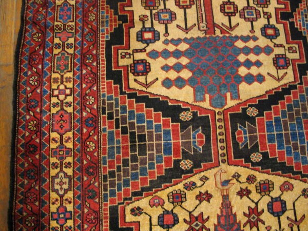 Geometric rug detail showing tan, red, blue, and black patterns, including stepped motifs, resting on wood.