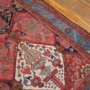 Geometric rug featuring red, navy, and light blue stylized patterns on light brown wood planks.