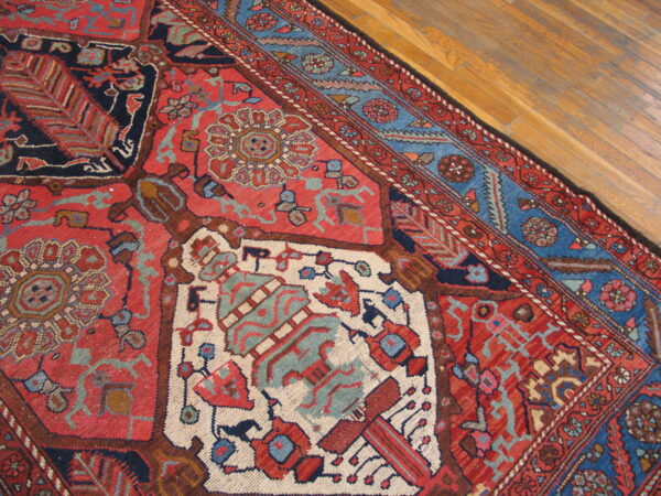 Geometric rug featuring red, navy, and light blue stylized patterns on light brown wood planks.