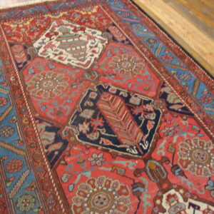 Red and blue traditional rug featuring medallions and geometric borders on light brown hardwood floors.