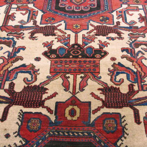 Low-pile rug detail showing a highly stylized geometric pattern with red, blue, black, and cream colors.