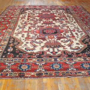 Cream, red, and black tribal rug featuring stylized geometric and animal designs on wood planks.