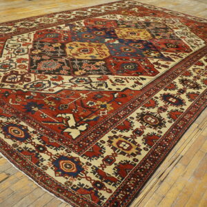 Red, cream, and blue traditional rug with a geometric grid pattern on antique wooden floors.