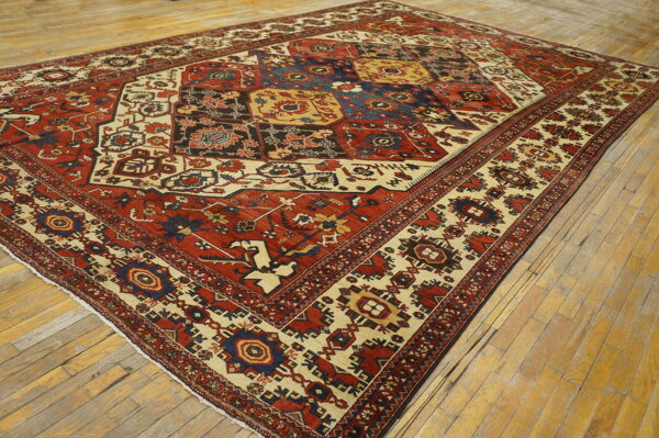 Red, cream, and blue traditional rug with a geometric grid pattern on antique wooden floors.
