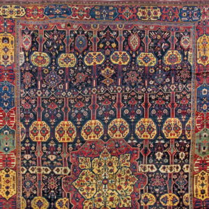 Intricate traditional rug pattern with a navy field, detailed red borders, and bright yellow medallions.