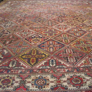Large multicolored rug displays a repeating geometric diamond pattern over a wooden floor.